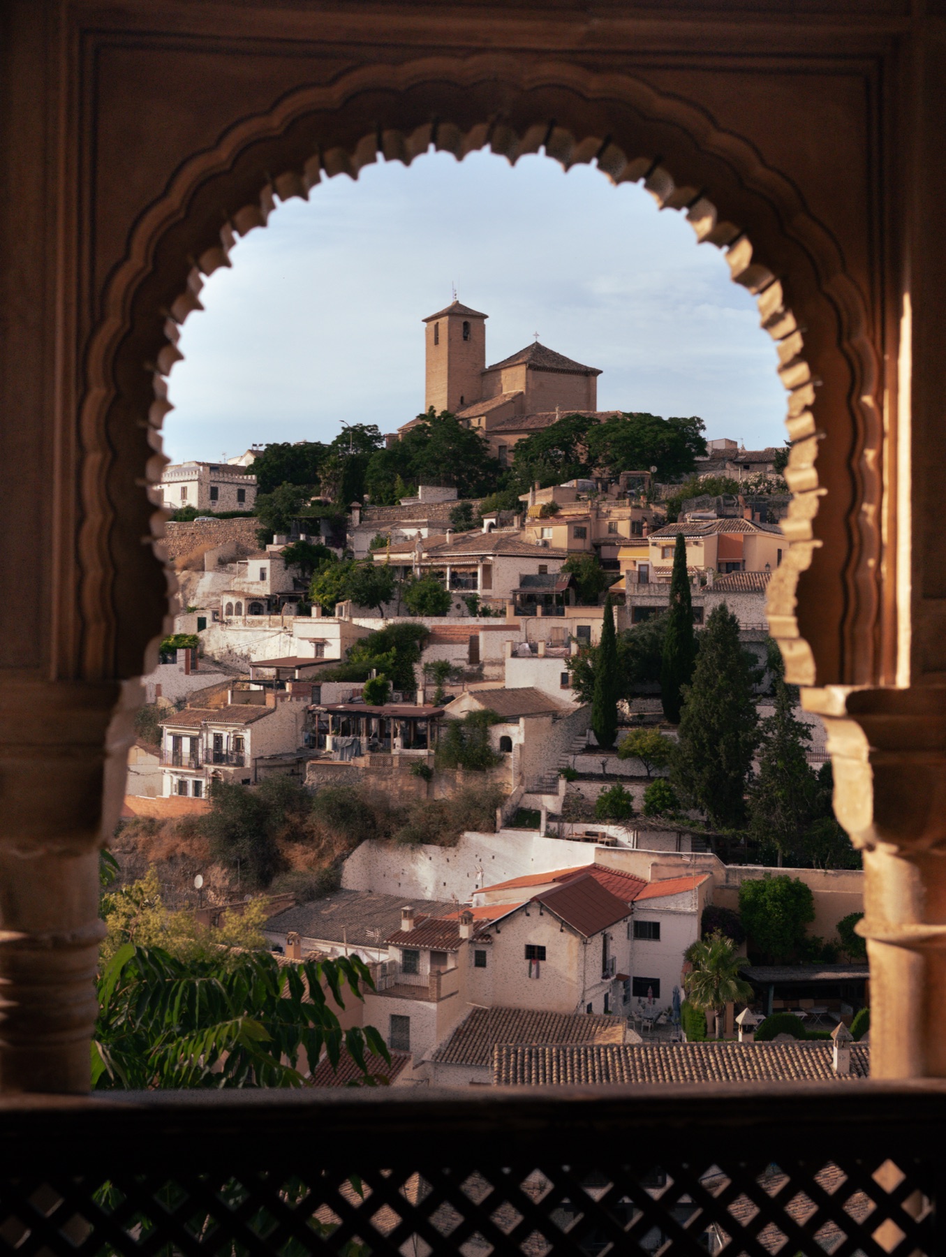 A hillside village of white houses framed by an ornate Moorish archway.