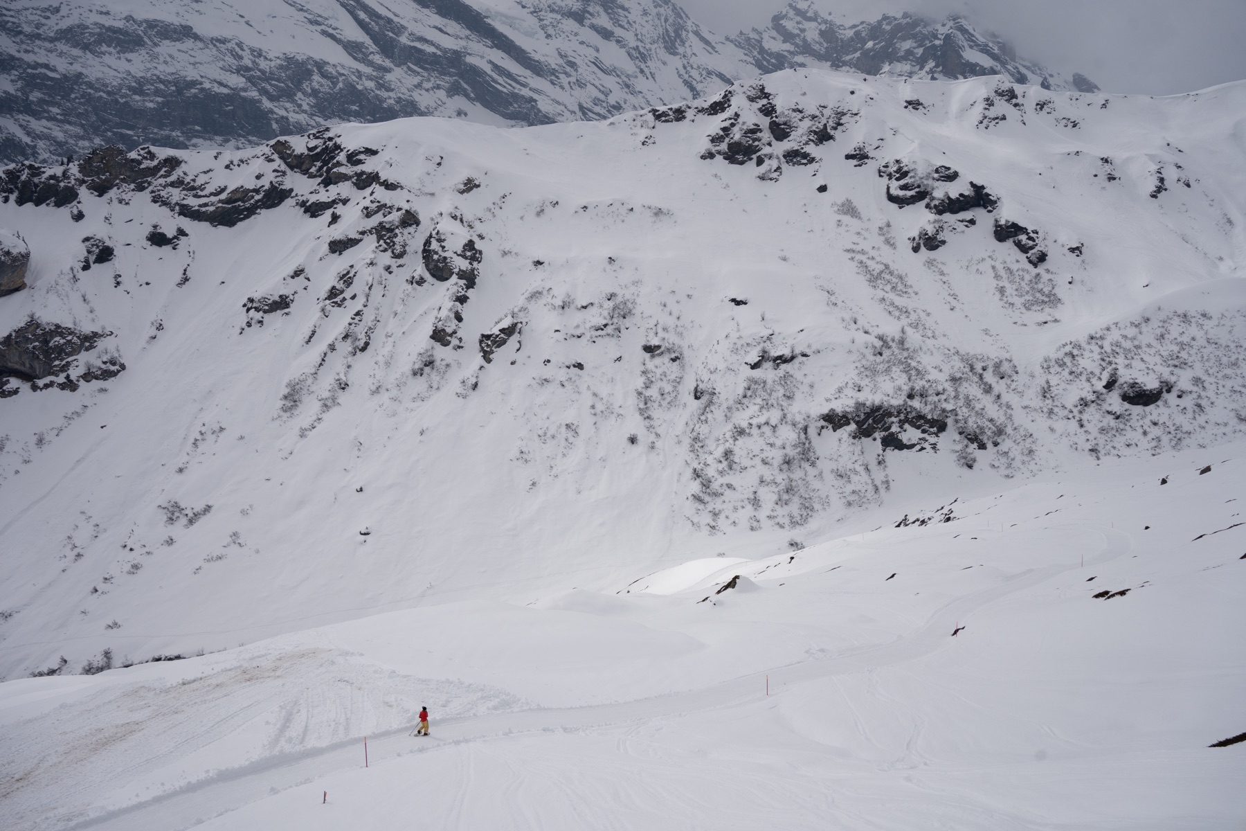 A lone skier descending a vast snow-covered mountainside.